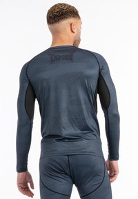 Dlhý rukáv športové tričko v tmavomodrej farbe s textúrovaným vzorom, čierne akcenty na pleciach a logo TAPOUT na chrbte.