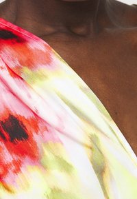 Mönstrad blommig topp i flera färger med ett lätt, genomskinligt tyg. Dominanta färger inkluderar rosa, röd och gul med en mjuk textur.