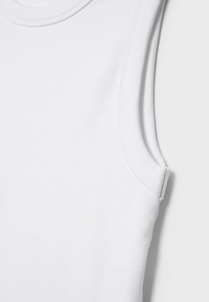 Detailní záběr bílé bezrukávové žebrované tílka zobrazující detaily švů u výstřihu a průramků.