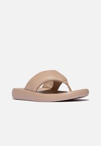Beige leren flip-flop sandaal met een ronde neus en een brede, gebogen band. Gladde textuur en een platte, gevoerde zool voor comfort.