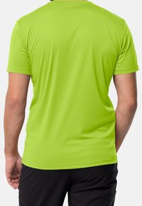 Krátký rukáv sportovní tričko v jasně zelené barvě. Vyrobeno z tkaniny odvádějící vlhkost, s hladkou texturou a uvolněným střihem.