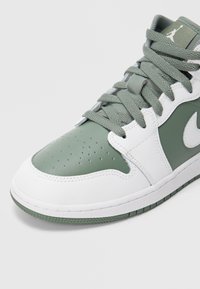 Zielono-biały sneaker z cholewką ze skóry i materiałów syntetycznych, perforacjami na palcach, płaskimi sznurowadłami oraz gumową podeszwą z fakturowanym bieżnikiem.