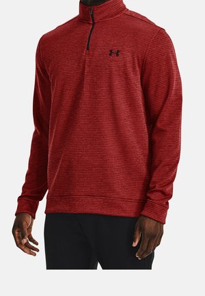 Punainen neljänneksen vetoketjulla varustettu paita, valmistettu teksturoidusta kankaasta. Ominaisuuksiin kuuluu musta rintalogo, pitkät hihat ja pystykaulus. Konepestävä.