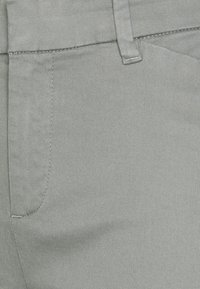 Pantaloni grigi chiari realizzati in tessuto testurizzato, con una vita standard e tasche laterali, accentuati da cuciture visibili.