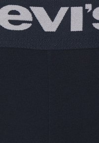 Sötétkék elasztikus derékpánt "Levi's" logóval fehér színben, texturált kötött anyagból. Simavásznú testanyag, testhez simuló fazon.