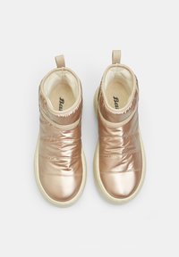 Botas de tobillo en rosa dorado metálico con un exterior acolchado, aberturas elásticas y suelas de goma de color claro. Presentan tiradores en la parte trasera.