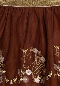 Bruine tule stof met een gouden tailleband, geborduurde gouden eenhoornhoofden versierd met roze, paars en crèmekleurige bloemen en bloemaccenten.