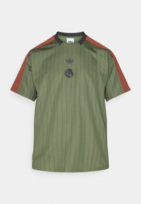 Camisa de manga corta color verde oliva con finas rayas verticales negras, rayas rojas en los hombros, cuello negro y dos logotipos bordados en el pecho.