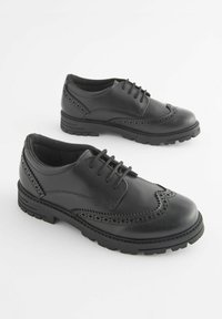 Pantofi din piele neagră cu design brogue, având detalii perforate, vârf rotund, șase găuri pentru șireturi și o talpă robustă din cauciuc.