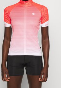 Jersey de ciclismo de manga corta en degradado de coral a blanco, con rayas horizontales y un cuello alto. Combinado con pantalones cortos de ciclismo negros.