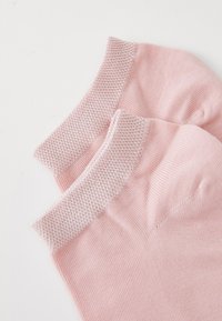 Um par de meias de algodão rosa claro com um punho de malha texturizada. Corpo suave e design canelado, apresentando biqueira e calcanhar reforçados.