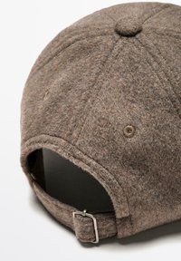 Cappello da baseball in feltro marrone con corona arrotondata, dettaglio del bottone e fascia regolabile con fibbia in metallo sul retro.