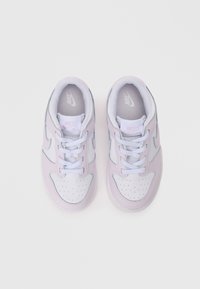 Nike sportcipő, fehér és világoslila bőr felsőrésszel, perforált orral és világoskék kiegészítőkkel. Normál fűzők és párnázott nyelv tartozik hozzá.