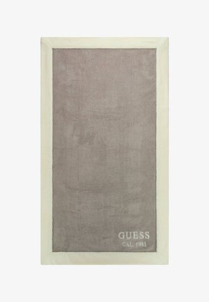 Harmaan pörröinen peitto, jossa on kermavärinen reuna, ja jossa on kohotettu teksti "GUESS CAL 1981" alakulmassa. Pehmeä pinta.