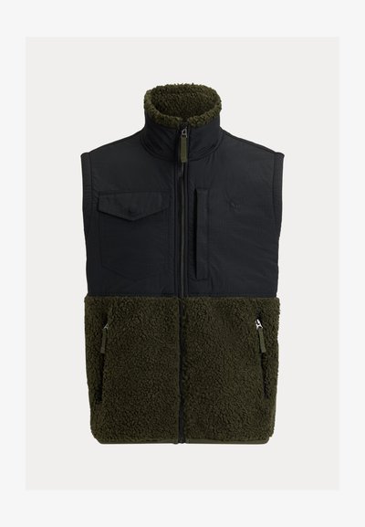 Schwarze isolierte Weste mit einem fellartigen, olivgrünen unteren Abschnitt. Sie hat einen hohen Kragen, Fronttaschen und einen Reißverschluss. Texturiertes Material.