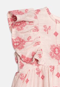 Světle růžový úplet s červenou květinovou výšivkou, se volánovými ramenními rukávy a nařaseným detailem v pase.