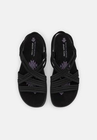 Mustat Skechers-muistivaahtosandaalit, joissa on useita ohuita ristikkäinjulkaisuja, avoimet varpaat ja takaosa hihnat.