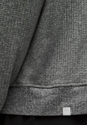 Pelēks teksturēts džemperis ar audumu rakstu, ribotām piedurknēm un mazu logo uzšuvumu apakšmalā. Mīksts audums ar strukturētu dizainu.