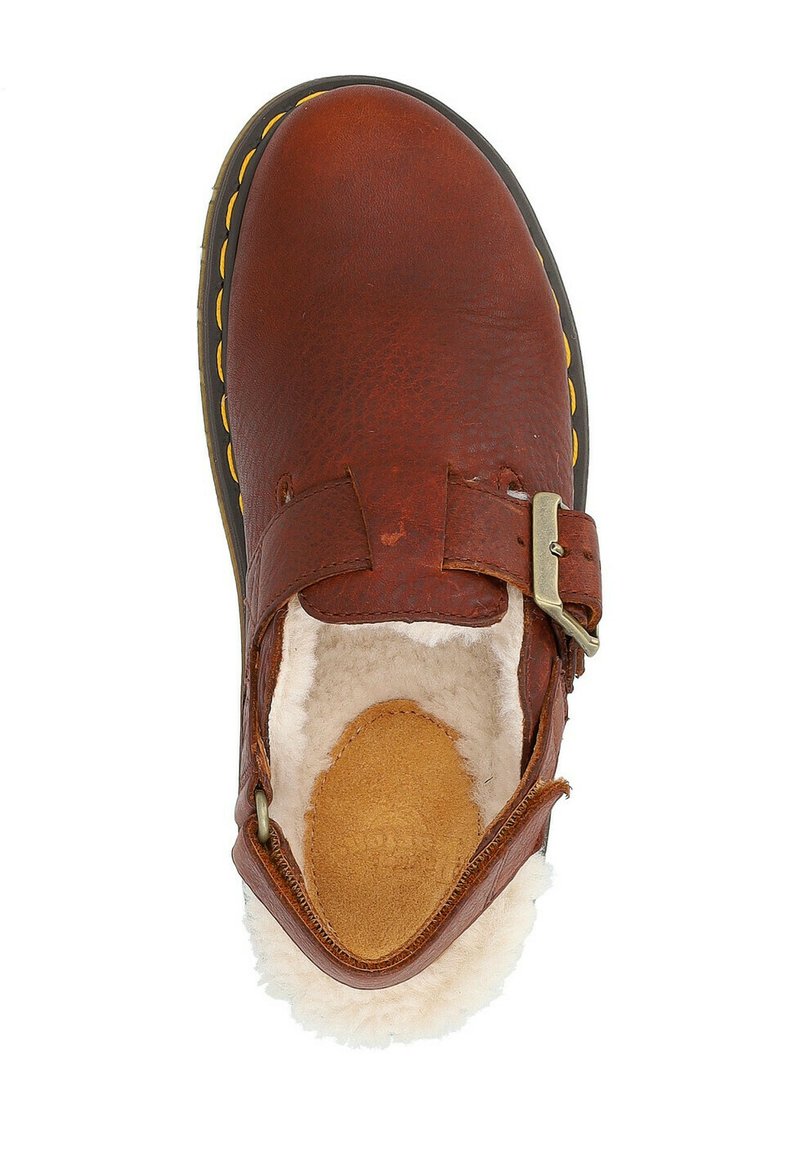 Chaussure en cuir marron avec une surface texturée, une sangle réglable et une doublure en polaire. Présente un détail de couture jaune autour de la semelle.