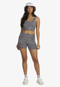Black and white striped crop top and shorts set, made from jersey fabric, with a loose fit. Worn with a white bucket hat and clogs.