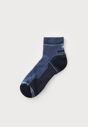 Navy-ankelstrümpfe mit einem strukturierten Muster, das unterschiedliche Blautöne und eine schwarze Zehenkappe aufweist. Beinhaltet dezente Branding-Elemente an der Seite.
