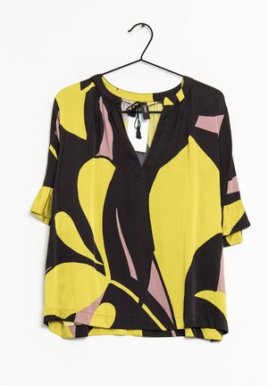 Black, yellow, and pink abstract floral blouse with 3/4 sleeves, V-neck with tie detail, hanging on a black hanger against white background.