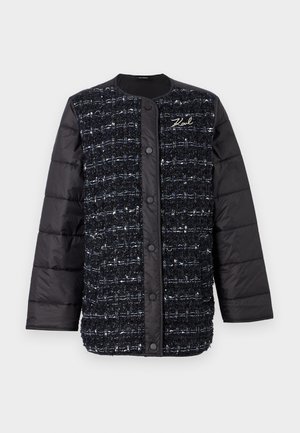 Musta ja tummansininen pehmeä takki, jossa on teksturoitu kangas etupuolella, nappilukko ja logo-ompelu. Liukuvat hihat ja helma.