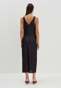 Schwarzes Midikleid mit V-Ausschnitt, gefertigt aus einem glatten, leichten Stoff mit feiner Textur. Akzentuiert durch dünne Schulterträger und einen geraden Schnitt.