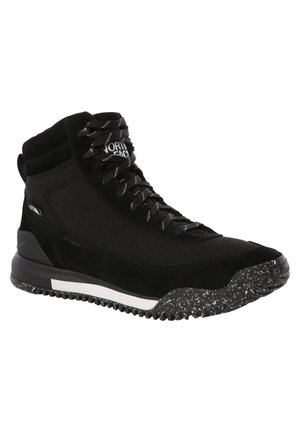 Baskets montantes noires avec lacets noirs, semelle texturée à taches blanches et logo de la marque sur la languette et le côté.