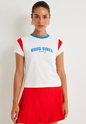 Witte T-shirt met korte mouwen, rode mouwen, blauwe halslijn en de print "GOOD VIBES only" in blauw en rood. Beschikt over een getailleerd ontwerp.