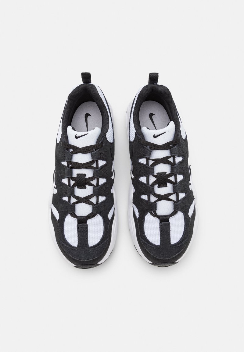Des baskets Nike présentant un design noir et blanc avec des matériaux en mesh et en daim, des surfaces texturées et un logo bien visible sur la languette.