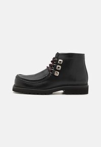 Bottes noires en cuir jusqu'à la cheville avec un bout arrondi, des lacets rouges et trois œillets en argent. Semelle texturée pour une meilleure adhérence et durabilité.