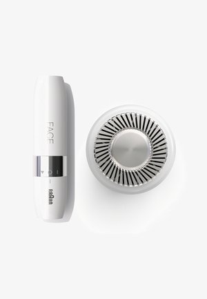 Appareil facial en plastique blanc avec une bande argentée et des icônes de contrôle ; la base circulaire présente des pales de ventilateur métalliques et un centre lisse.