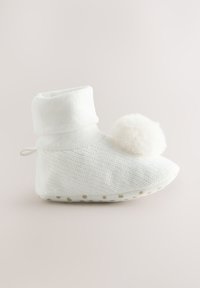 Chausson tricoté blanc avec un revers côtelé, un pompon en fausse fourrure douce et une semelle en caoutchouc à points pour la traction. Design simple et confortable.