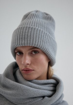 Szary, prążkowany zimowy beret wykonany z miękkiego dzianiny, w komplecie z dopasowanym szarym szalikiem, wyróżniający się grubą teksturą i jednolitą konstrukcją.