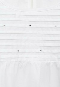 Top in tessuto bianco con pieghe orizzontali e paillettes sparse. Il colletto è rotondo e la texture sembra morbida e leggera.