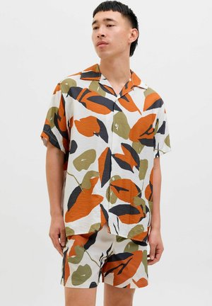 Conjunto de camisa de mangas cortas y pantalones cortos en una tela ligera y texturizada. Presenta un patrón de hojas multicolores en naranja, verde, negro y blanco.