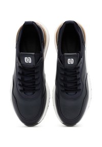 Marineblauwe leren sneakers met een gestructureerd oppervlak, witte zool en contrasterende tan accenten. Beschikt over een vetersluiting en een logo op de tong.