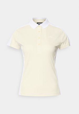 Polo color beige chiaro con colletto bianco. Presenta una patta con tre bottoni e un logo sul lato sinistro. Maniche corte e tessuto dalla texture liscia.
