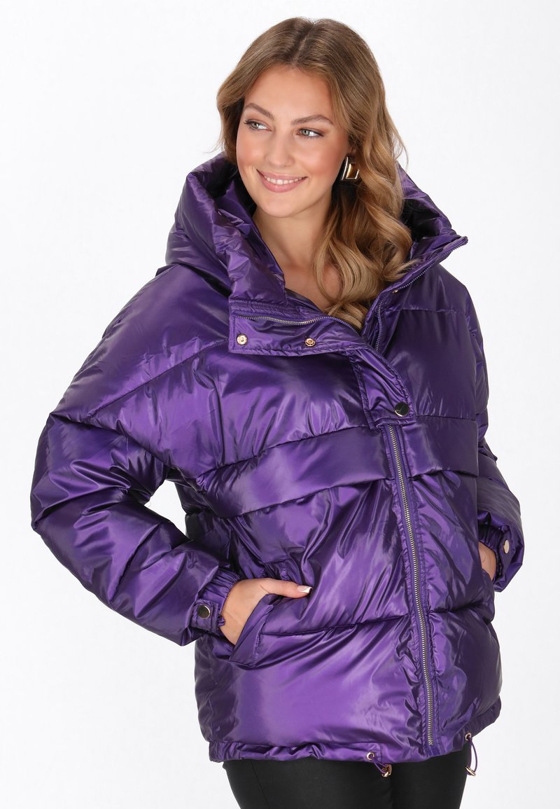 Lila puff jacket magas gallérral, fényes textúrával, elülső cipzárral és oldalsó zsebekkel. Deréknál húzózsinórral van ellátva az állítható illeszkedés érdekében.