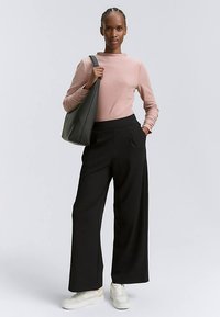Hellrosa enger Pullover, weite schwarze Hosen, weiße Sneakers und eine graue Schultertasche. Glatte Textur mit minimalistischem Design.