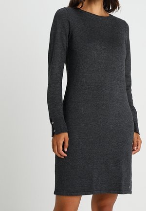 Langarmige donkergrijze gebreide jurk met knoopmanchetten, gedragen door een staand persoon, zichtbaar van nek tot midden bovenbeen.