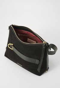 Borsa in suede nera con cerniera dorata, fodera rosso scuro e manico in pelle testurizzata. Presenta un design minimalista e dettagli dorati.