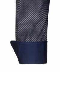 Polsino della camicia blu navy con un piccolo motivo geometrico in oro e bianco. Il tessuto appare liscio con una consistenza leggera e una finitura pulita.
