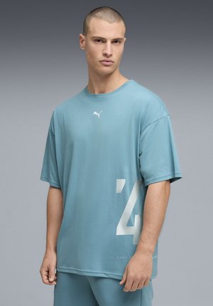 Miętowa koszulka Puma z krótkimi rękawami, okrągłym dekoltem i dużym białym nadrukiem cyfry '4' z boku. Wykonana z miękkiej, gładkiej bawełny.