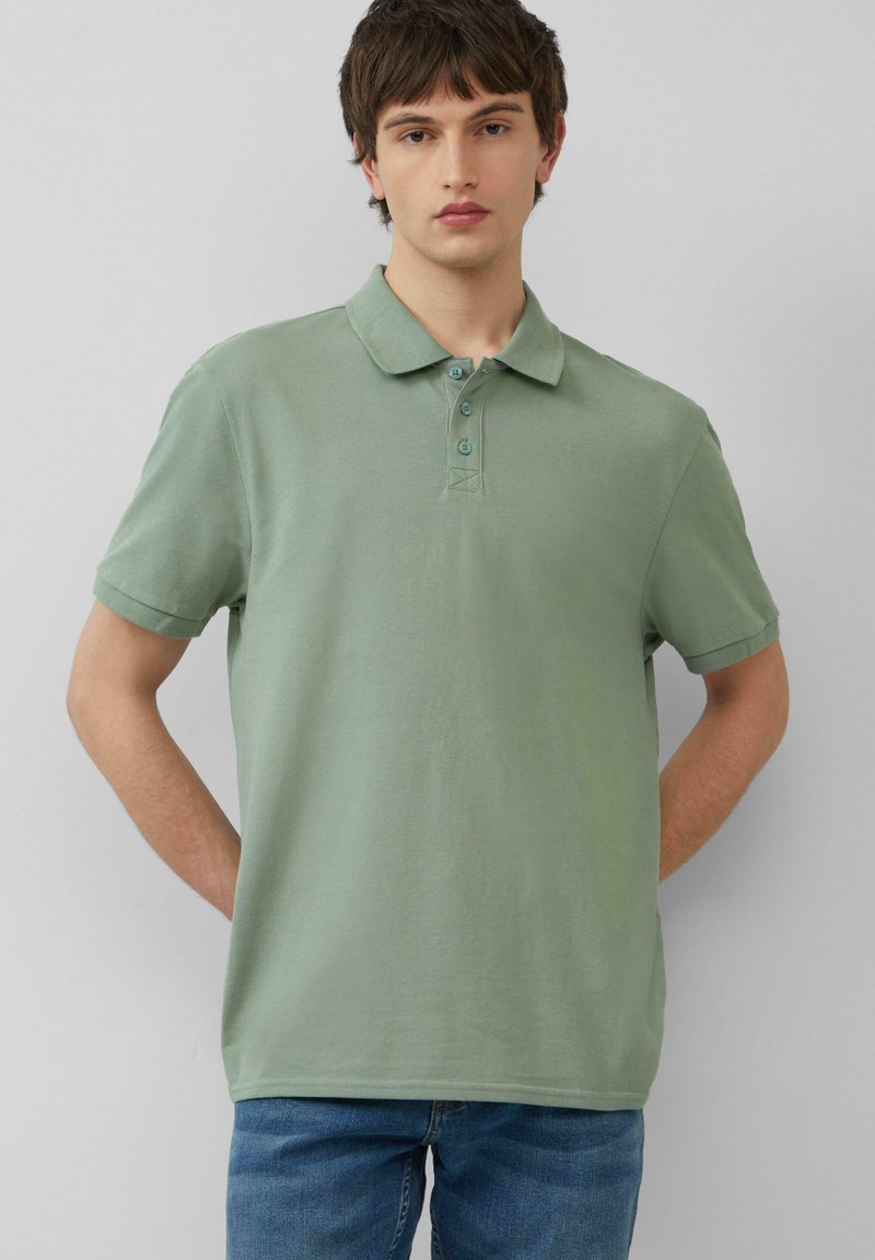 Polo de manga corta en un color verde apagado, con un cierre de tres botones y una textura suave, similar al algodón.