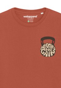 T-Shirt aus Baumwolle in Rostfarbe mit einem grafischen Design eines Kettlebells und dem Text "No Pain No Gain" in einem kräftigen, strukturierten Stil.