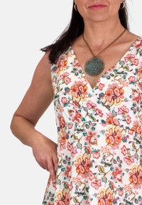 Vestido floral en blanco con patrones coloridos que presentan flores rosas, naranjas y verdes. Acentuado con un gran collar de colgante texturizado.