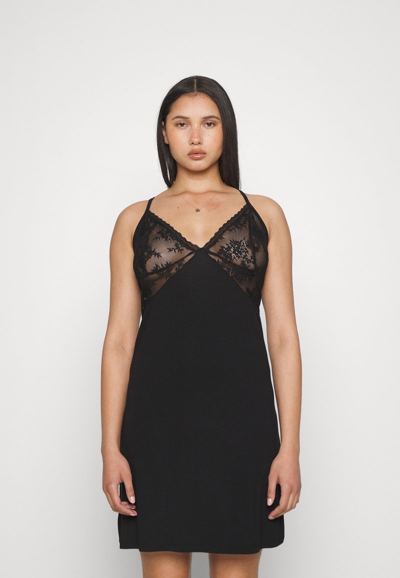 Robe noire avec un décolleté en V, ornée de dentelle transparente et de bretelles réglables. Le tissu est lisse et présente une silhouette ajustée.