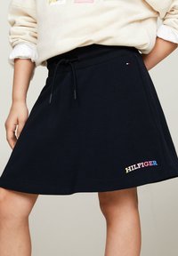 Falda azul marina hecha de una mezcla de algodón, con cintura elástica y logotipo bordado "HILFIGER" en múltiples colores en el dobladillo.